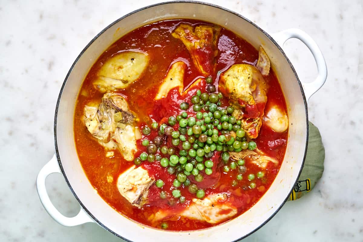 White pot of chicken stew with green sour grapes.