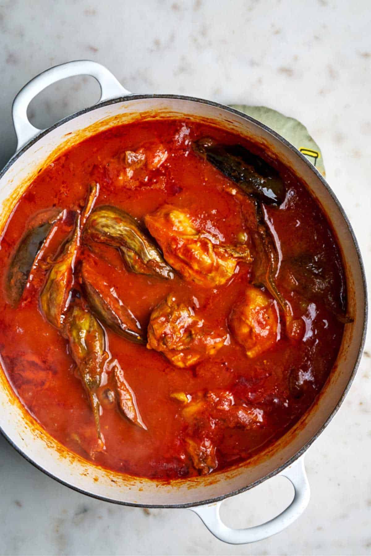 Top view of cooked eggplant stew with chicken in red sauce.