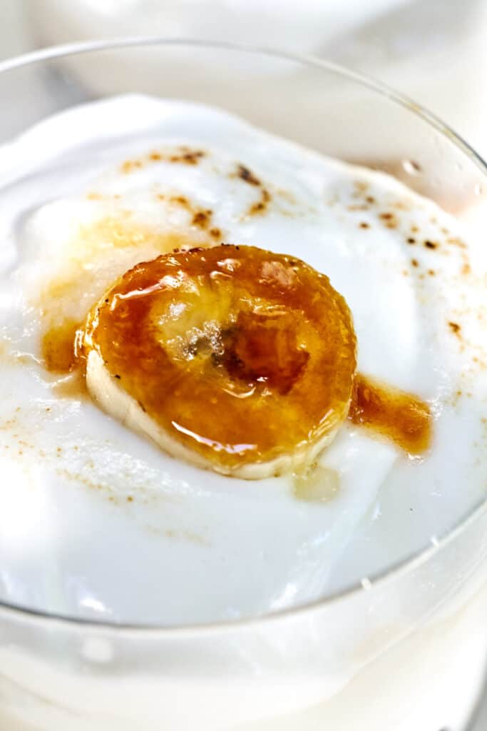 Close up of whipped cream topped with a bruleed banana slice.