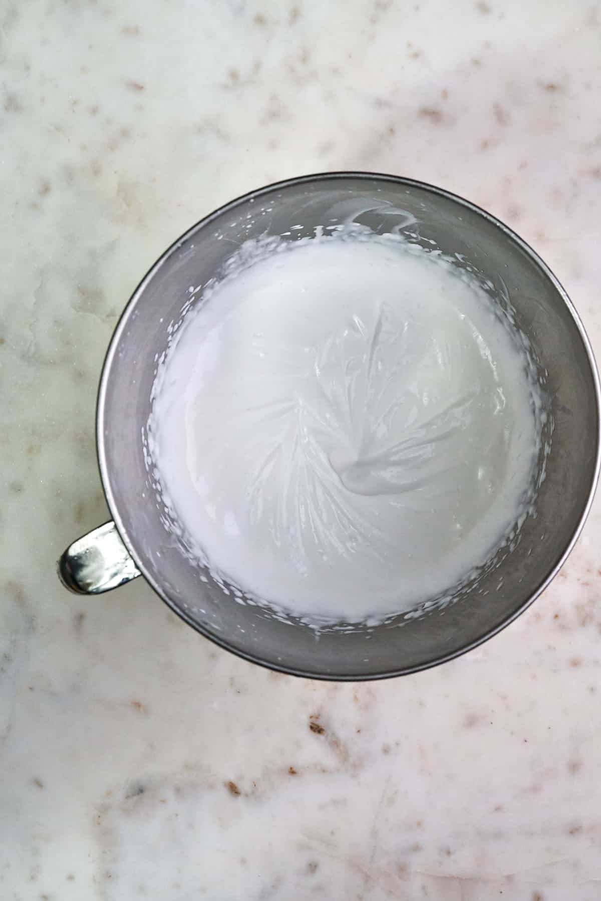 Texture of coconut whipped cream in a mixer bowl.