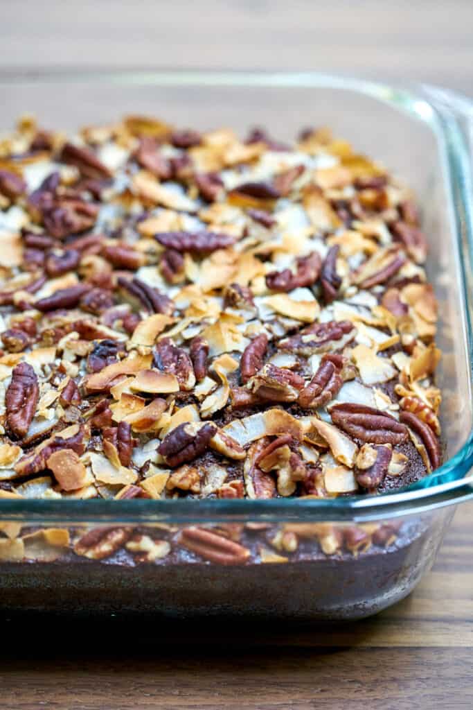 Cake in a glass baking dish covered in pecans and coconut after baking.