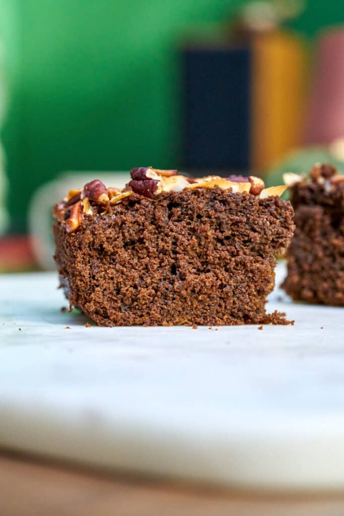 Front view of one piece of cake on a white table with green background.