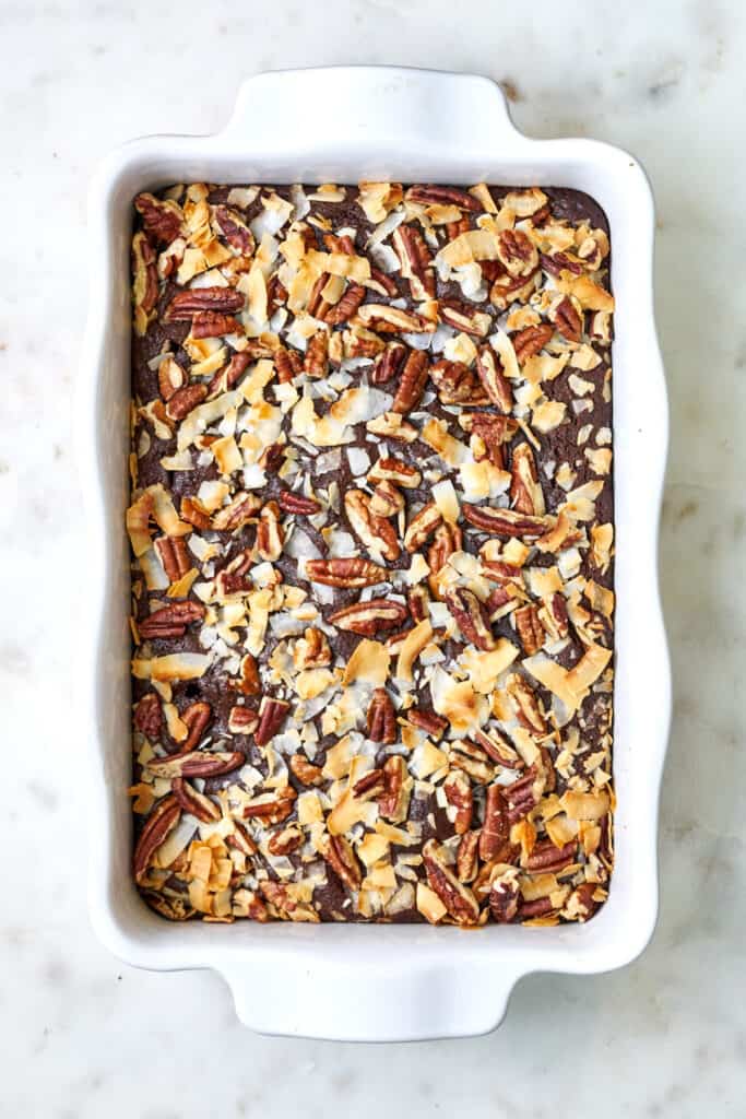 Top view of cake in white dish topped with coconut and pecans.