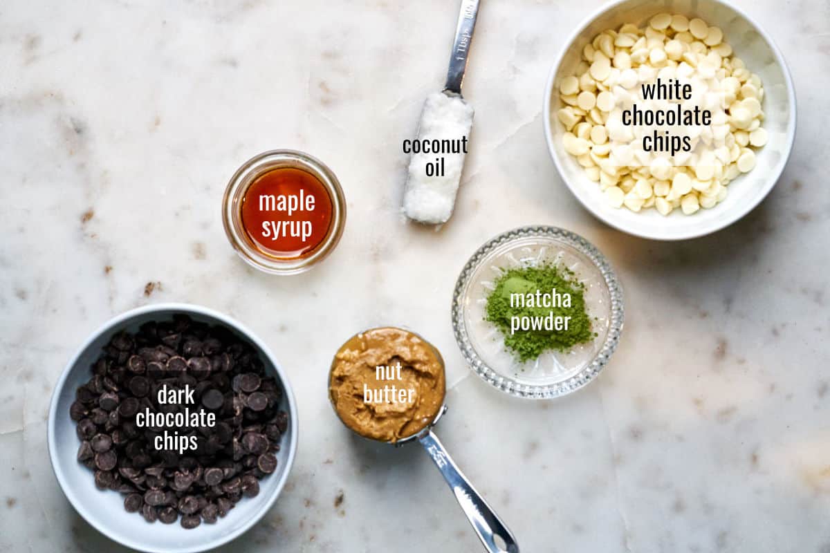 Ingredients on a white countertop including white and dark chocolate chips.