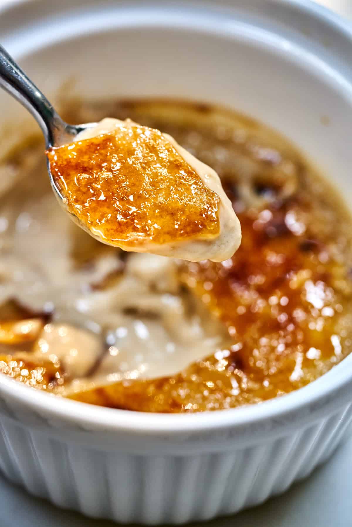 Close up of a bite of creme brulee on a spoon.