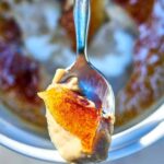 Top view of creme brulee on a spoon resting on a ramekin.