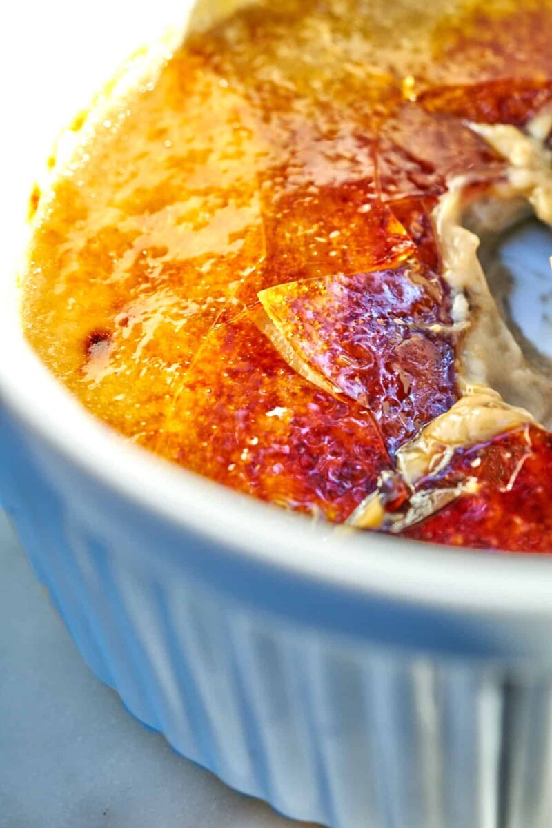 Close up inside a ramekin filled with cracked sugar and creme brulee.