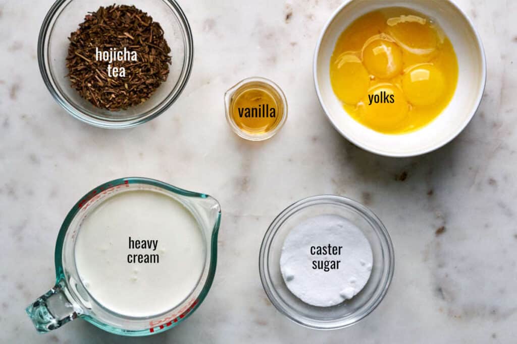 Tea, yolks, vanilla, cream, and sugar on a white countertop.