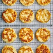 Twelve cooked latkes on a wire rack.