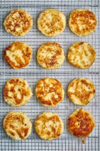 Twelve cooked latkes on a wire rack.