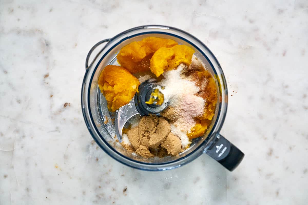 Food processor bowl filled with pumpkin and spices.