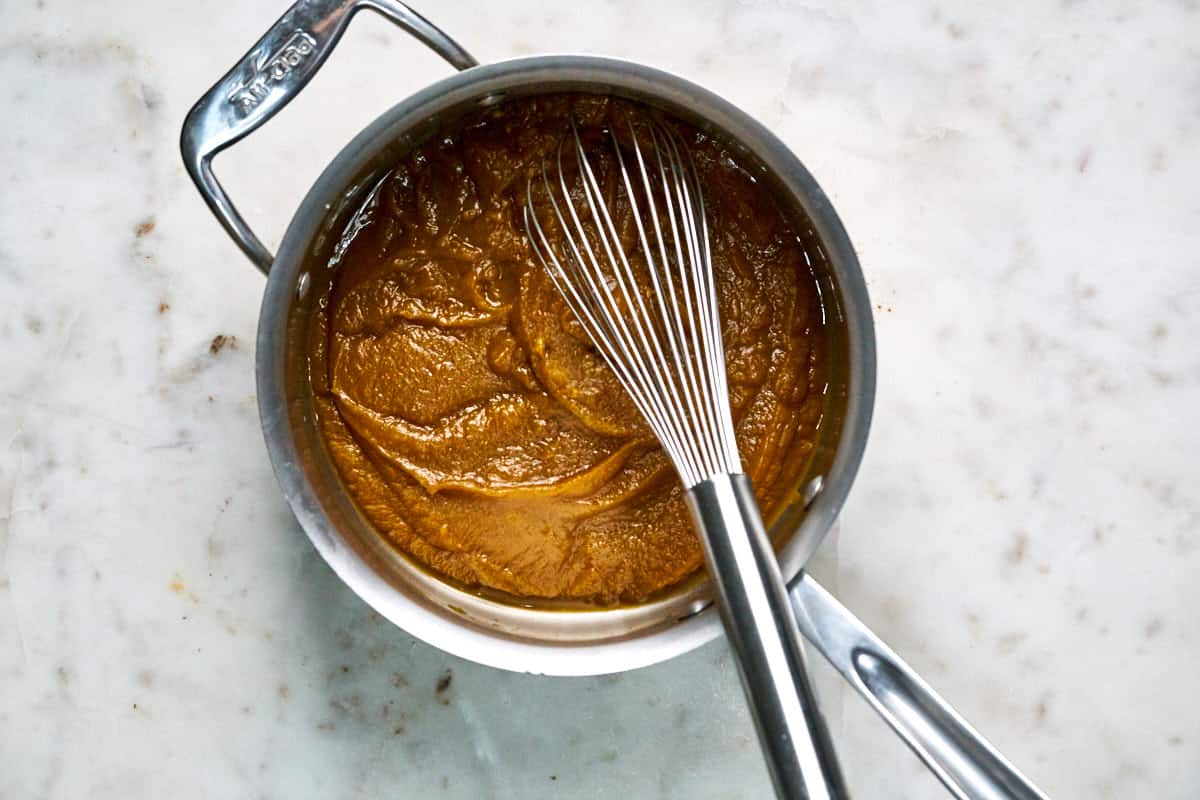 Pumpkin cooking in a saucepan with a whisk.