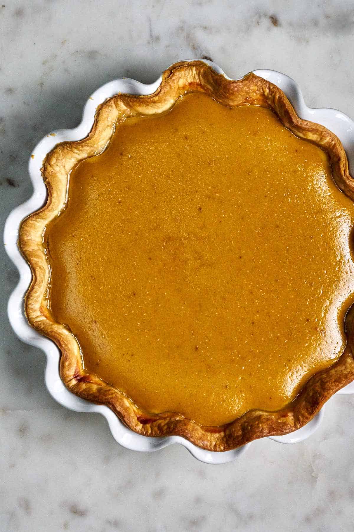 Top view of a pumpkin pie in a white ruffled pie dish.