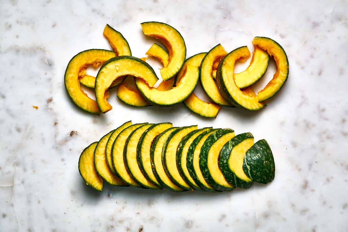 Slices and wedges of kabocha squash on a white countertop.