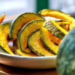Roasted kabocha squash on a white plate on a wood table.