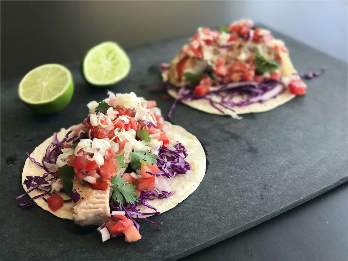 Two tacos on a cutting board.