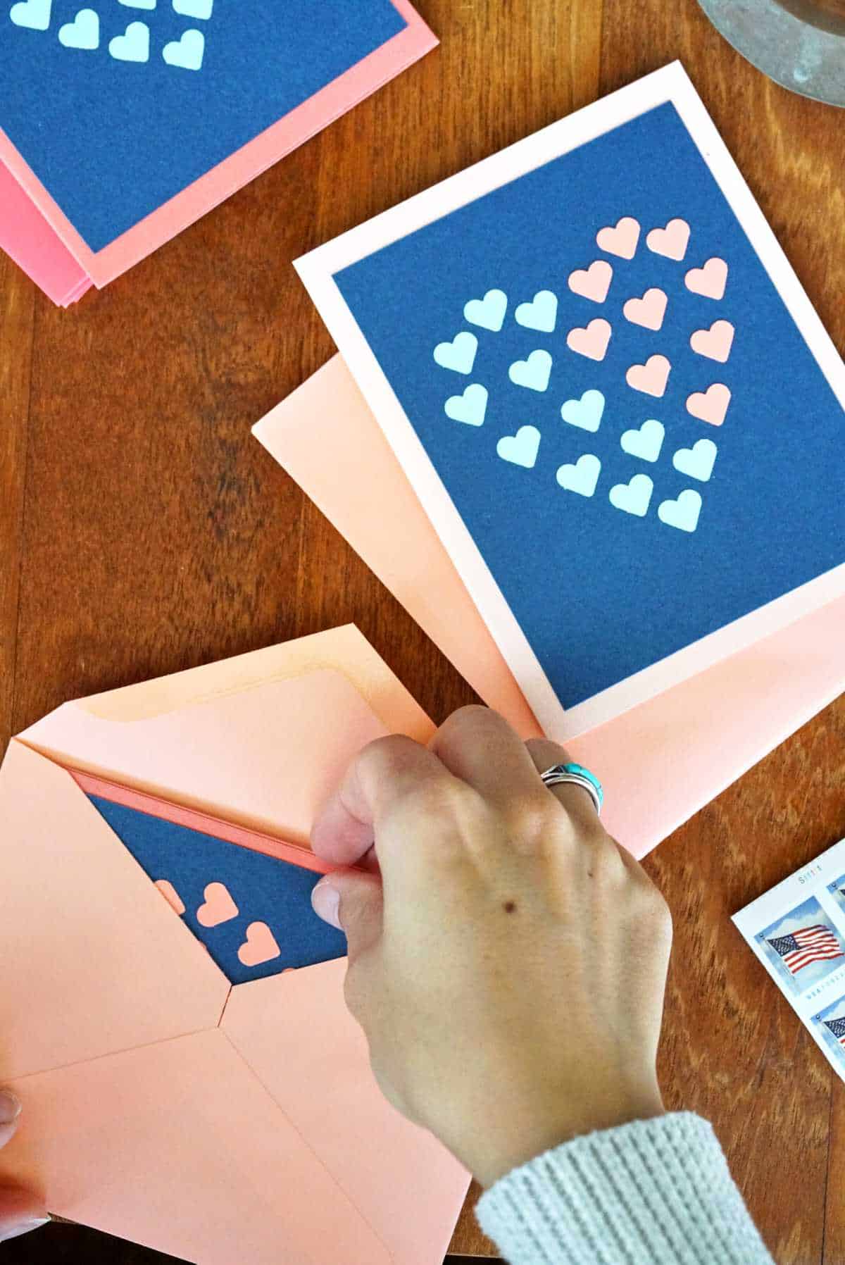 Putting cards with hearts into envelopes.