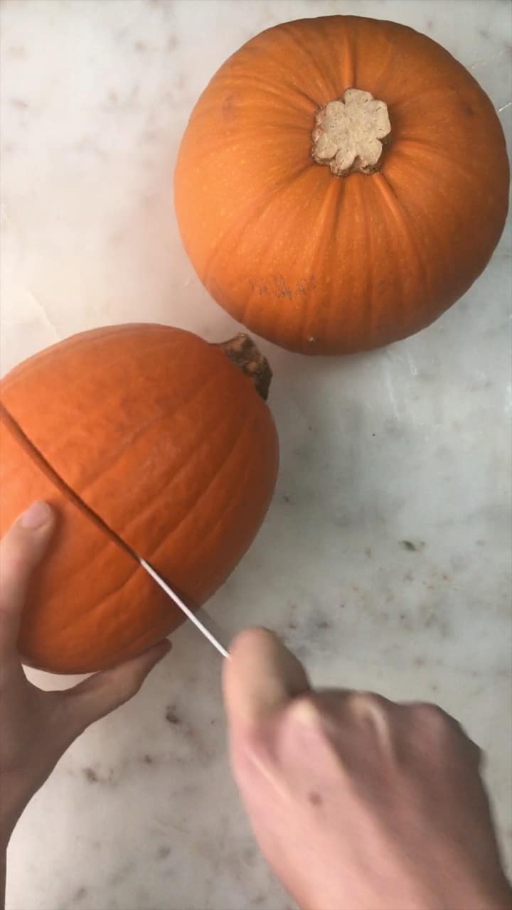 Cutting a pumpkin in half lengthwise.