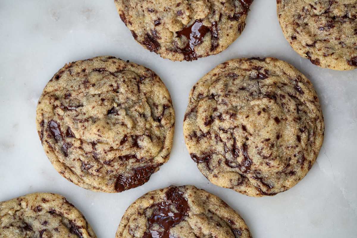 Several chocolate chip cookies laid out on a marble countertop.