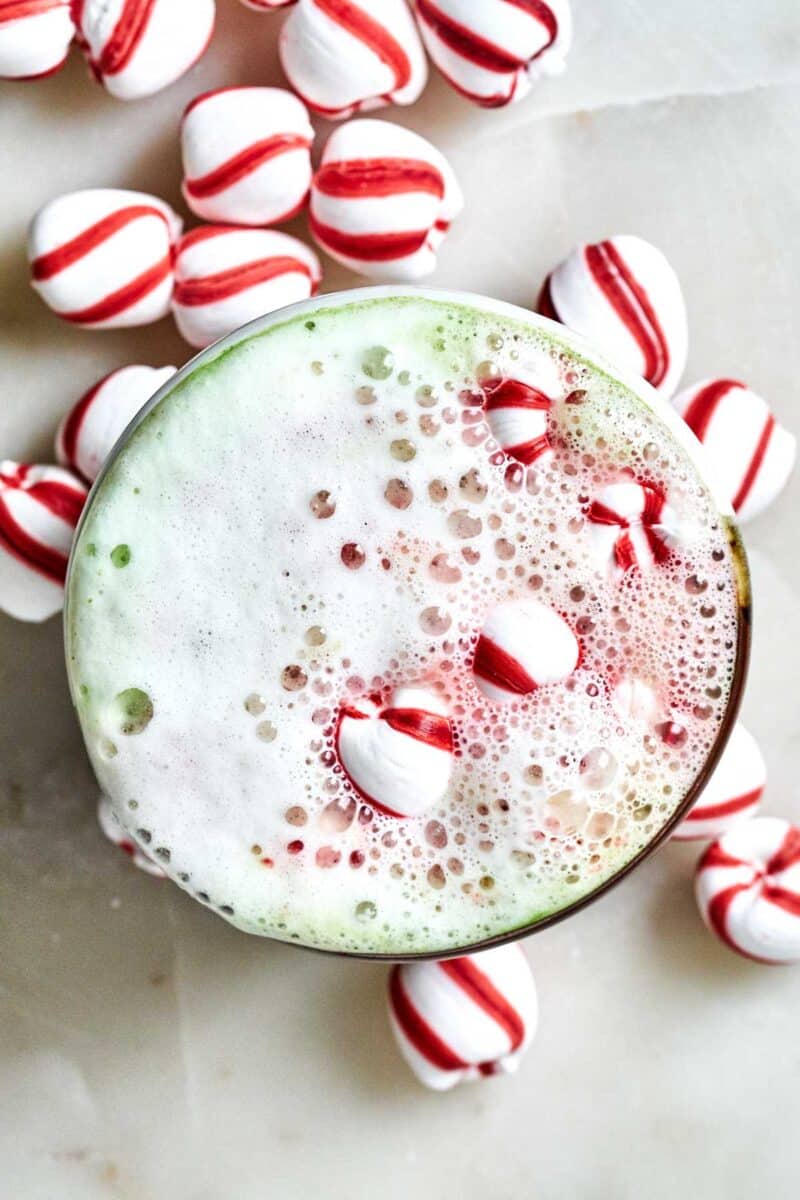 Green and red latte with candy cane candies.