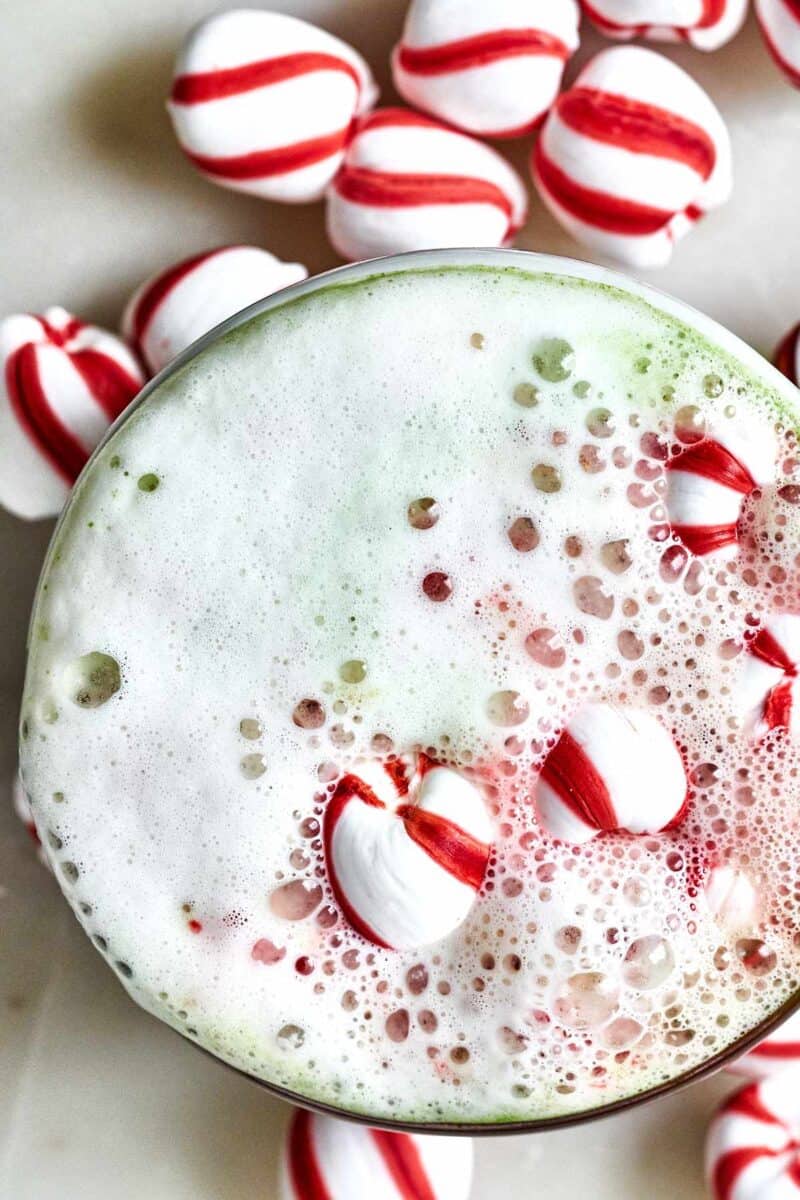 Green and red latte with candy cane candies.