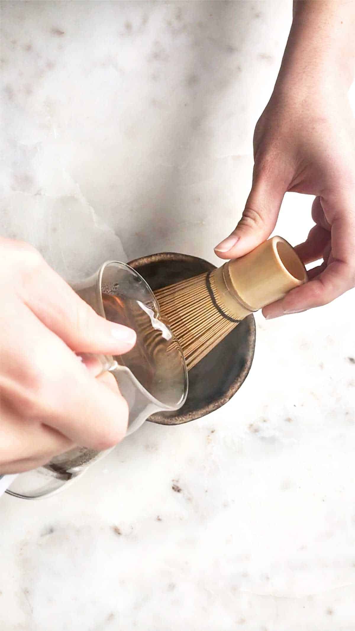 Pouring tea onto chasen in a bowl.