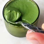 Scooping green pudding on a spoon.