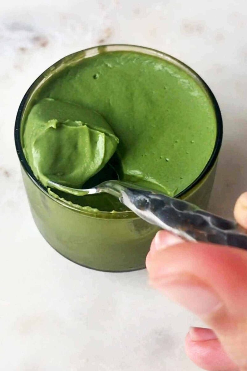 Scooping green pudding on a spoon.