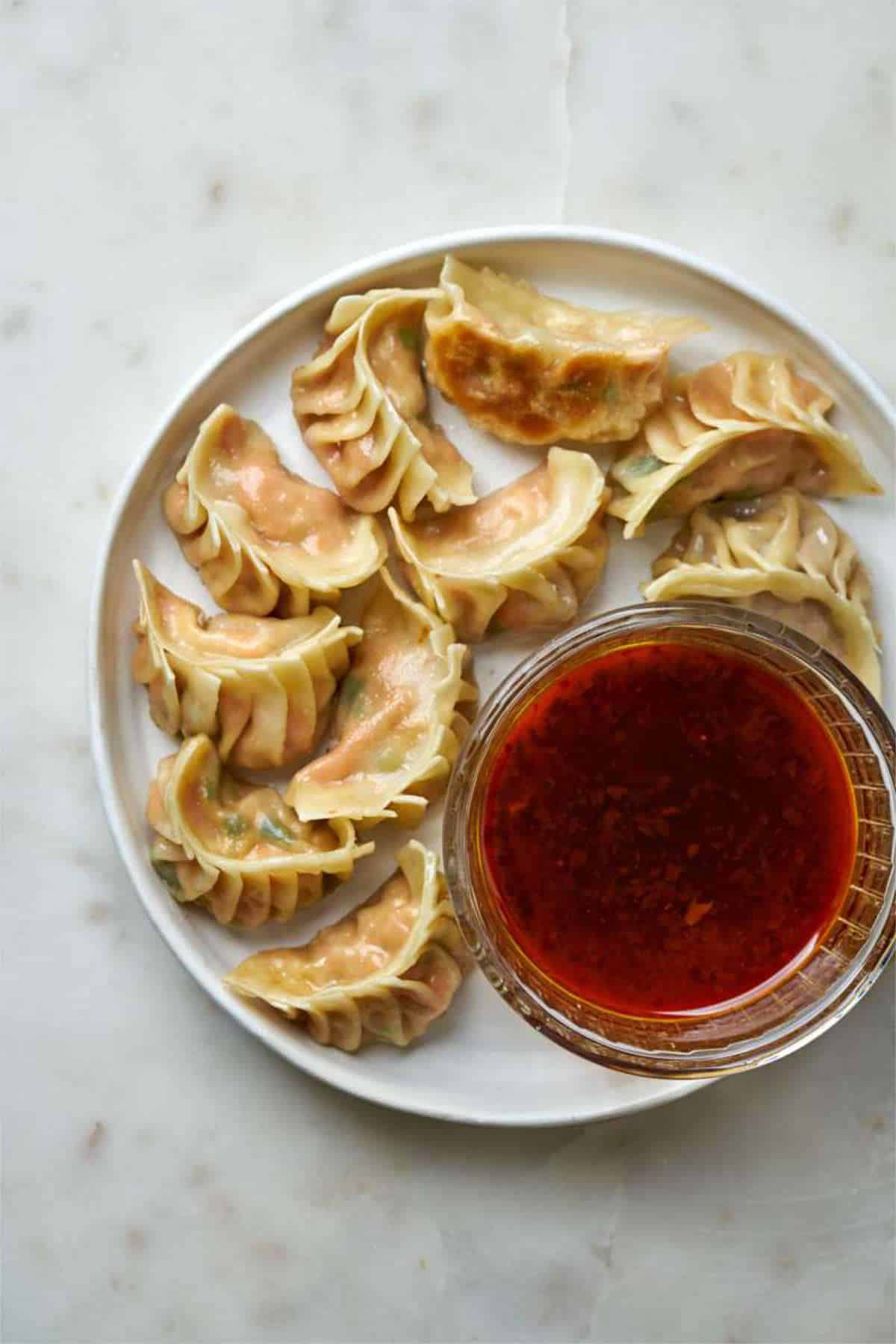 Cooked potstickers on a plate with dipping sauce.