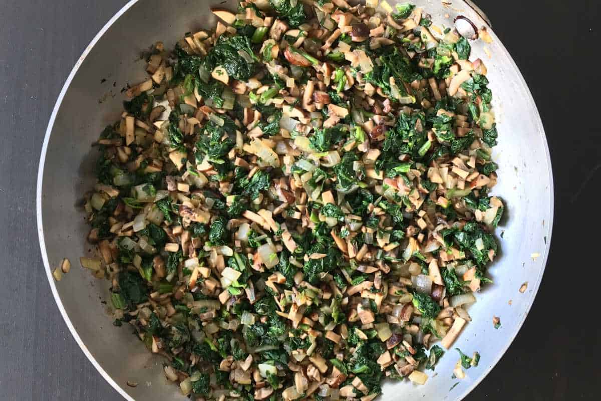Spinach mixture cooking in a pan.