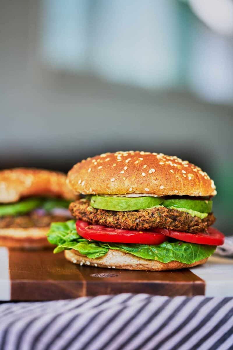 Two burgers on a cutting board.