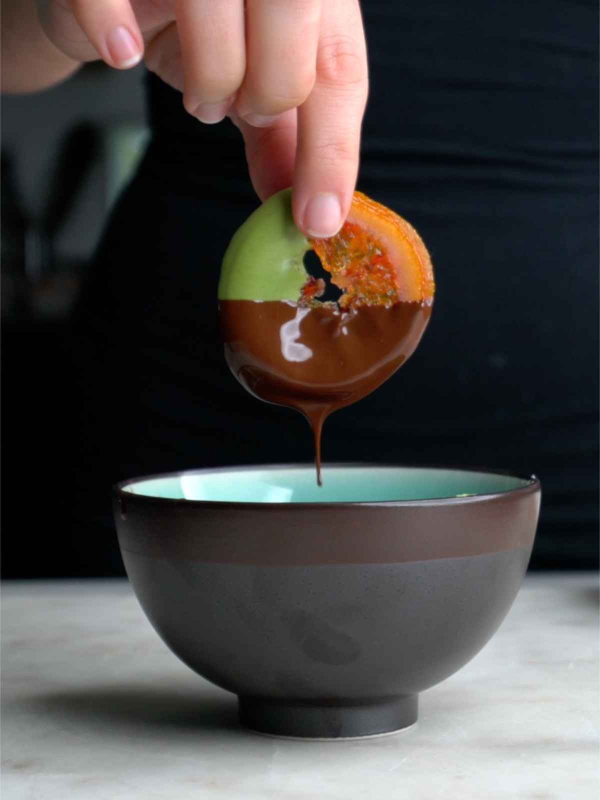 Dipping a candied orange in chocolate.