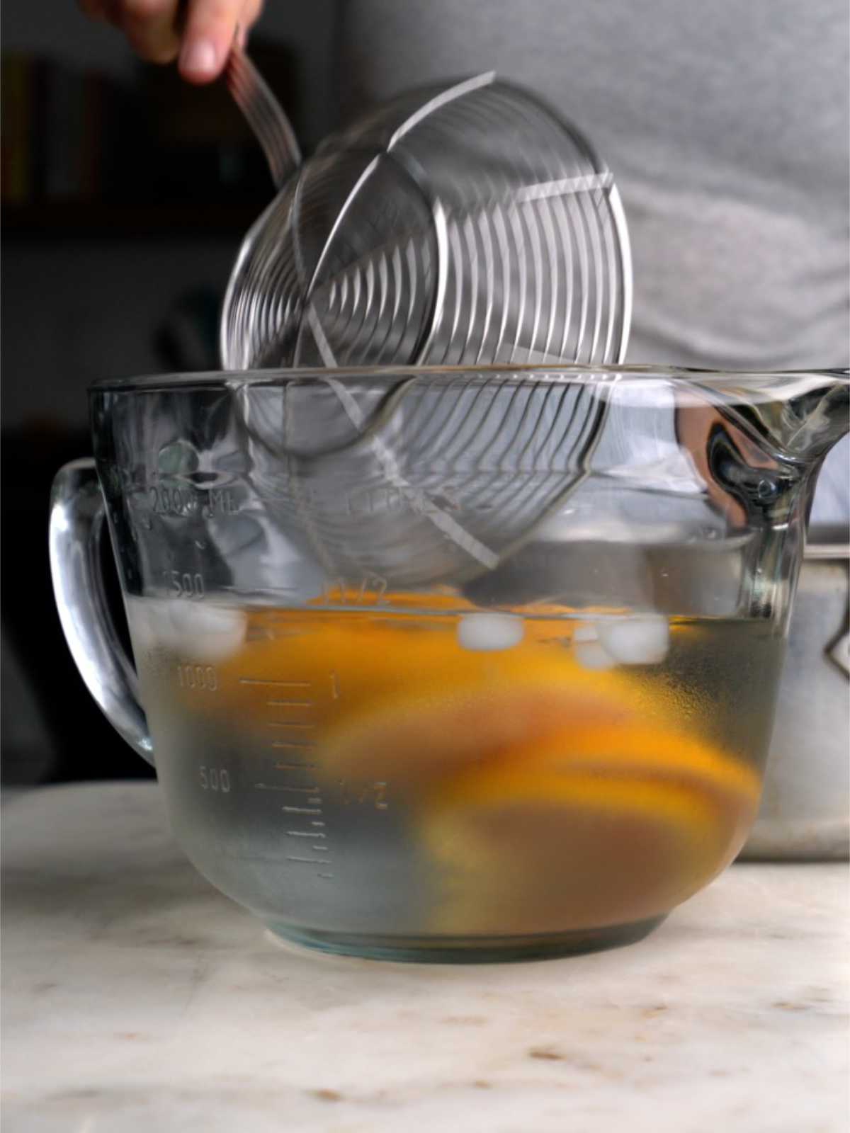 Adding orange slices to an ice bath.