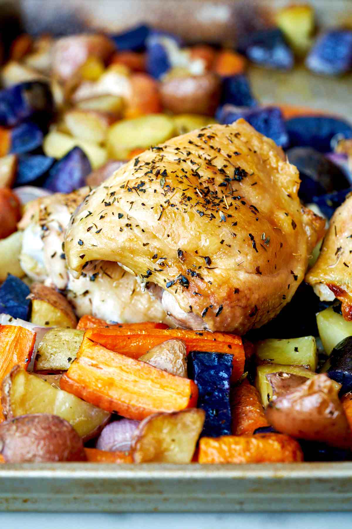Cooked chicken thigh and root vegetables.