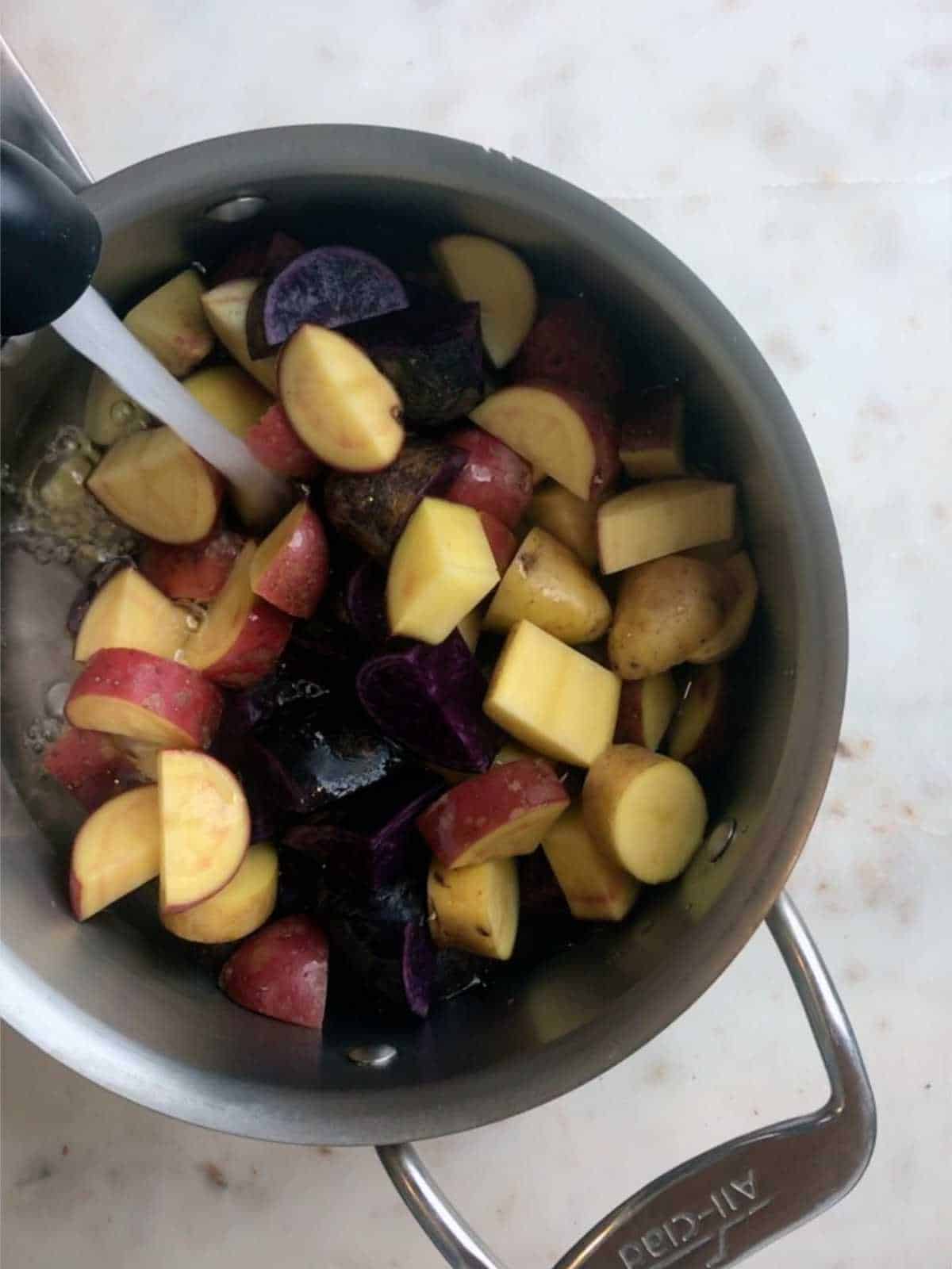 Filling pot of potatoes with water.