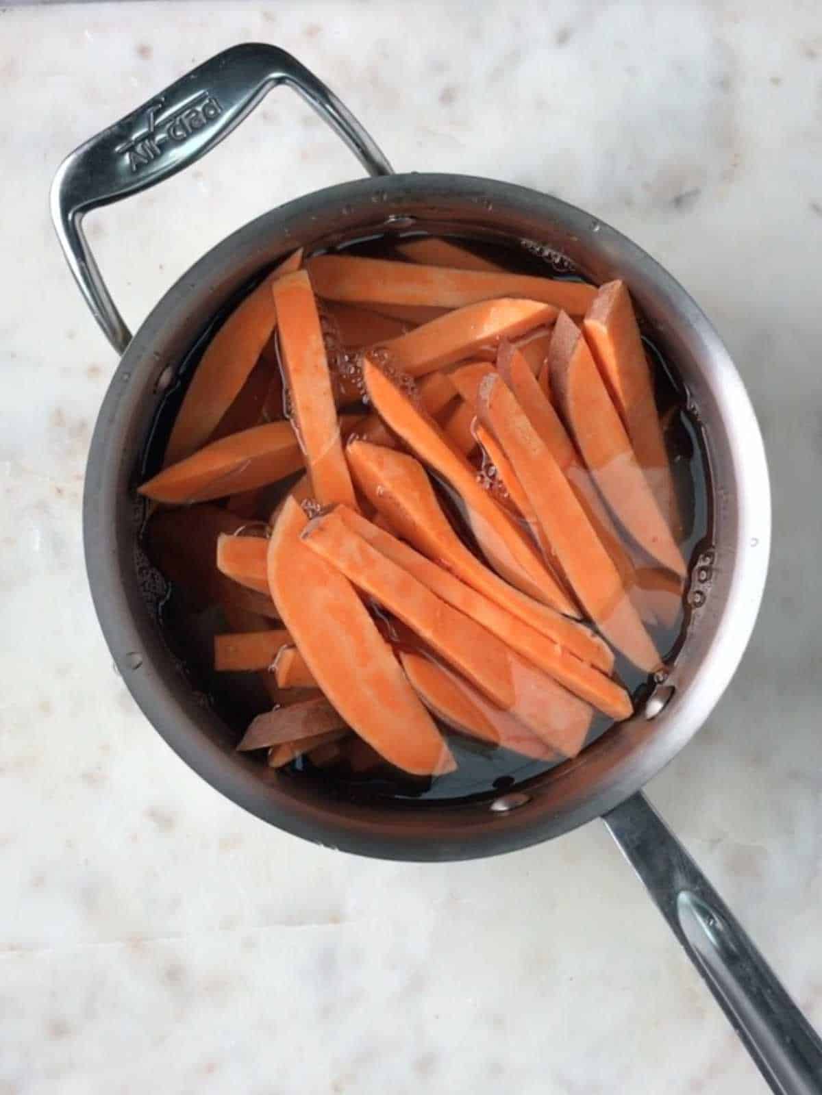 Sweet potato fries in a pot of water.