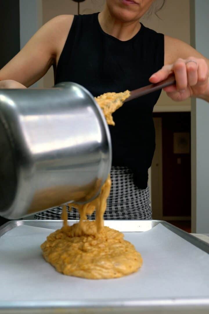 Pouring toffee on a baking sheet.