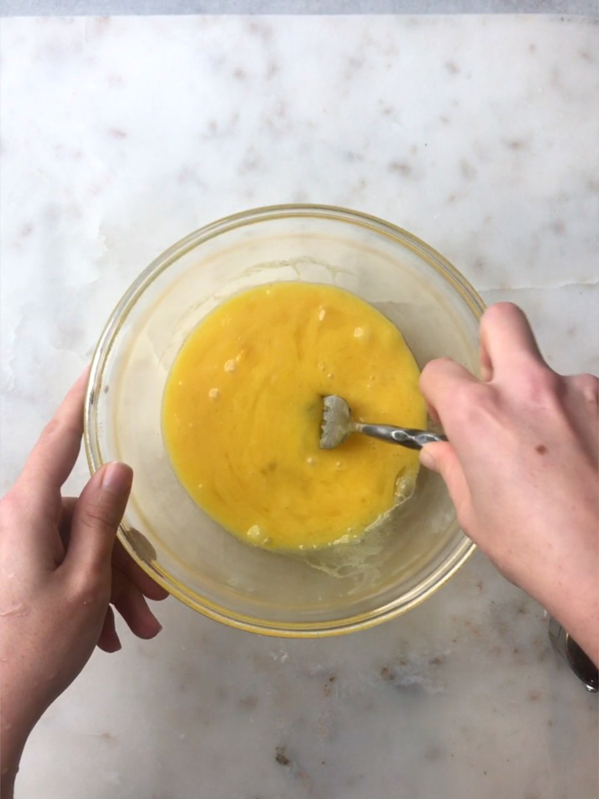 Scrambled eggs in a glass bowl with a fork.