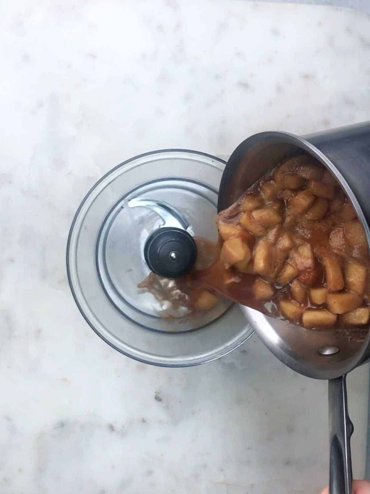Pouring cooked apples into food processor bowl..