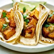 Three potato tacos with cilantro and lime.