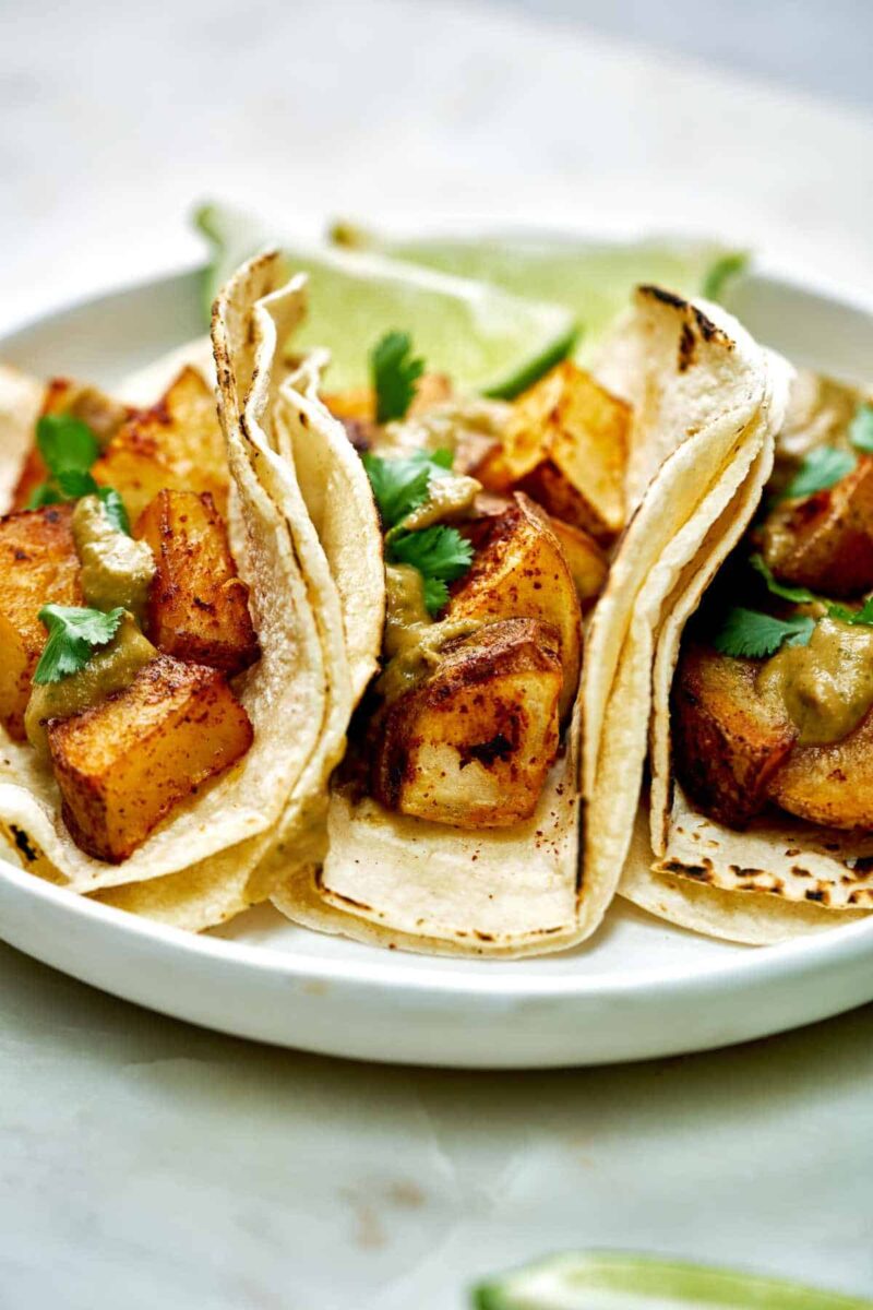 Three potato tacos with cilantro and lime.