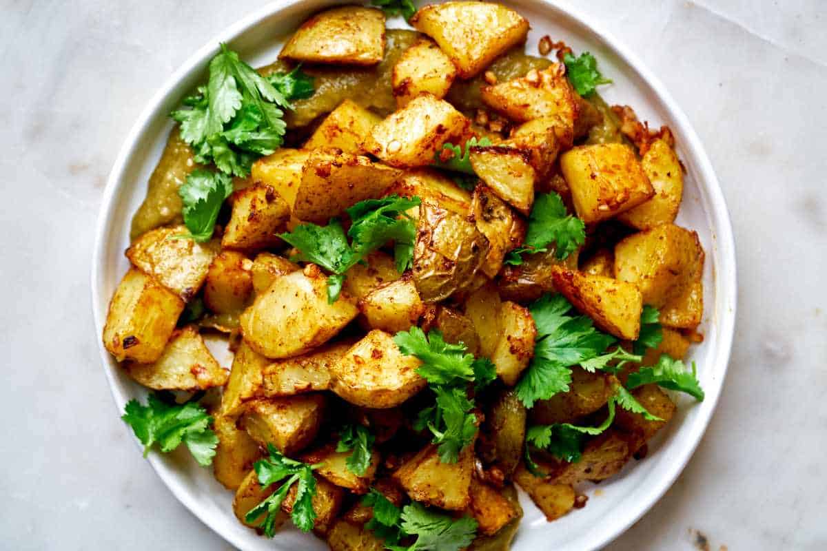A plate of potatoes with cilantro and salsa.