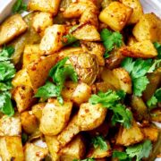 A plate of potatoes with cilantro and salsa.