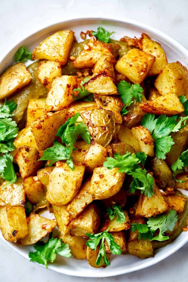 A plate of potatoes with cilantro and salsa.