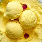 Scoops of yellow ice cream with rose petals.