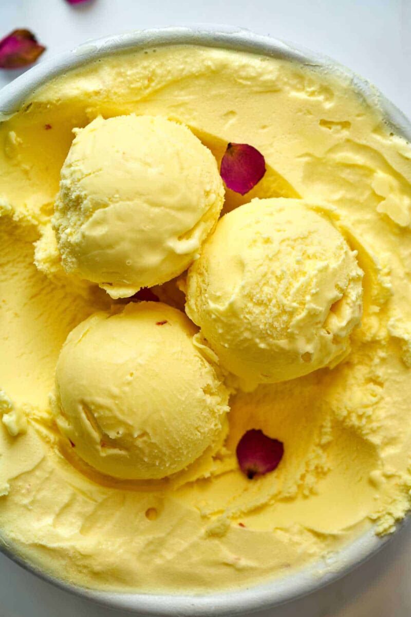 Scoops of yellow ice cream with rose petals.
