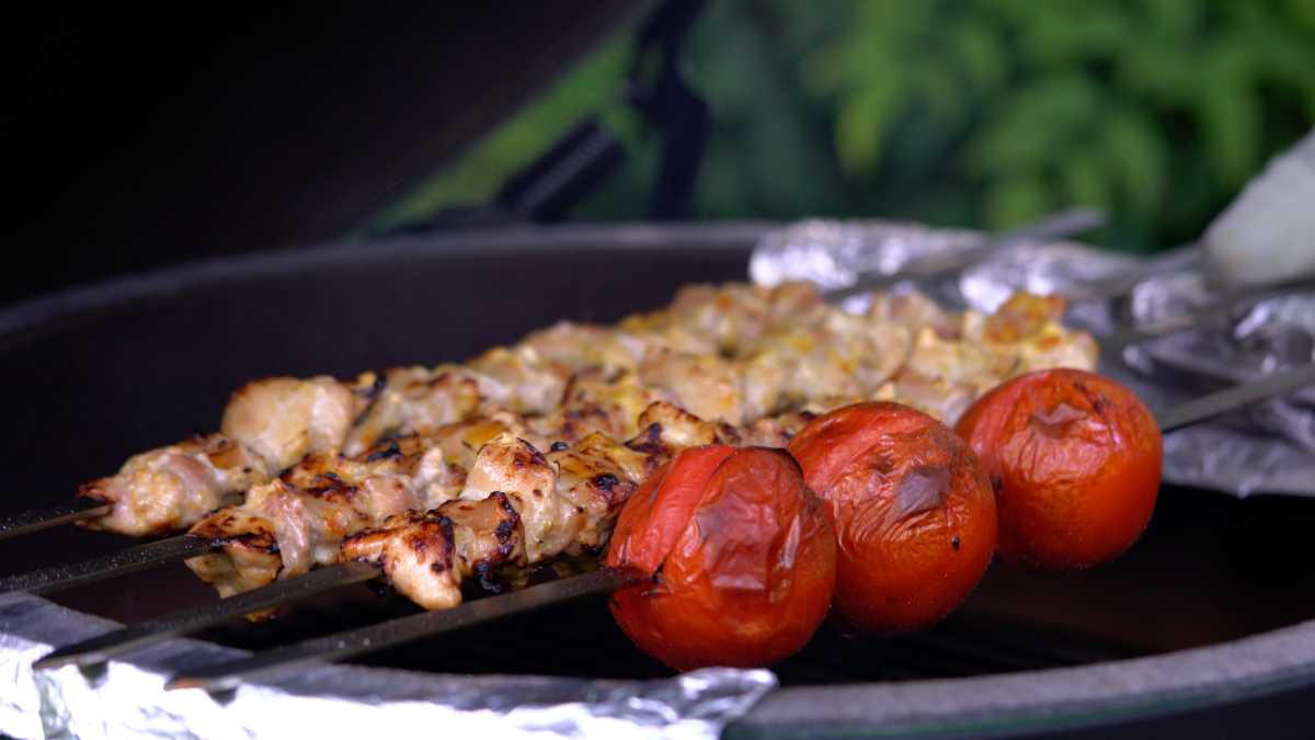 Chicken and tomatoes on a grill.