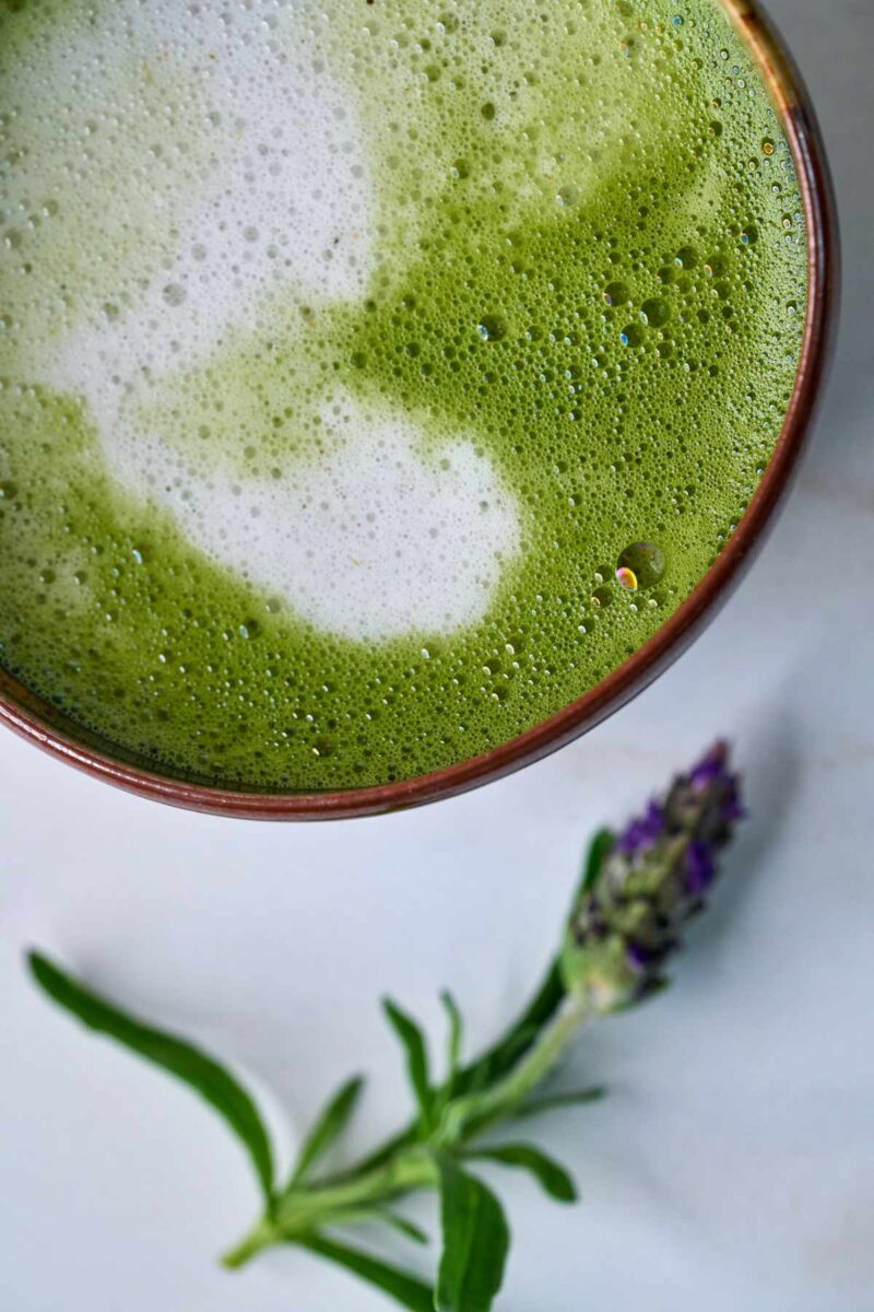 Green latte next to a sprig of lavender.