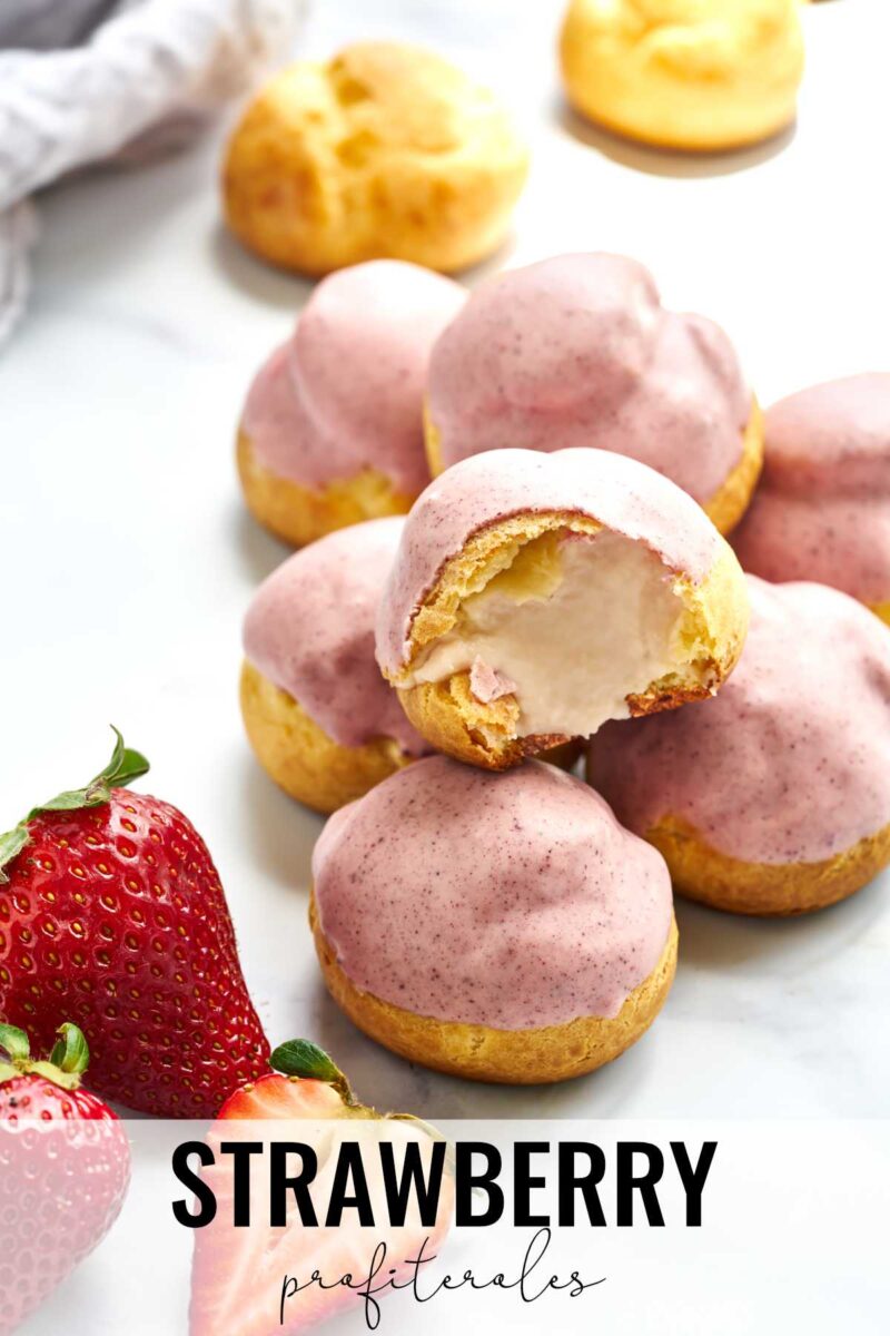 Stack of pink cream puffs next to strawberries.