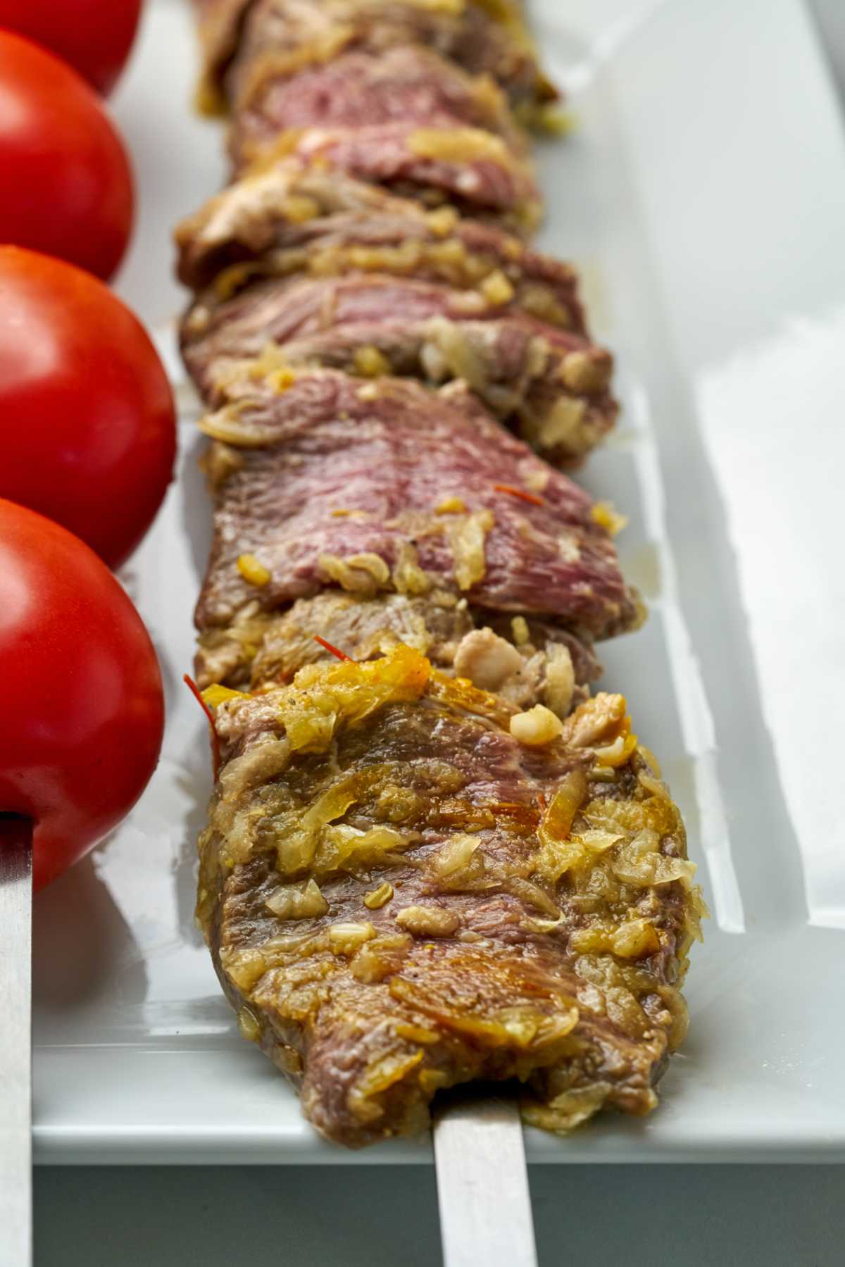 Raw kabob and tomatoes on a plate.